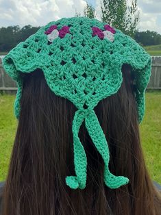 the back of a woman's head wearing a green crocheted hat with flowers