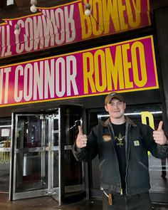 a man standing in front of a building giving the thumbs up