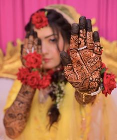 a woman holding up her hands with henna tattoos on it's palms and flowers in front of her face