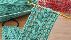 a green crochet afghan next to a pair of scissors on a wooden table