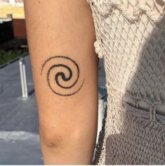 a woman's arm with a tattoo on it that looks like a spiral design