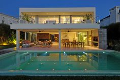 a large house with a pool in front of it at night, lit up by lights