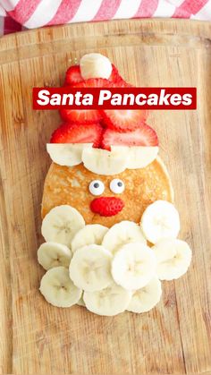 a wooden cutting board topped with pancakes and sliced strawberries on top of each other