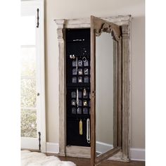 a mirror that is next to a wall with jewelry hanging on it and an armoire in the corner