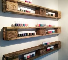 two wooden shelves filled with different types of nail polish on top of each other in front of a white wall