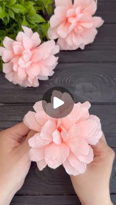 someone is holding some paper flowers in their hands and making them look like they are floating