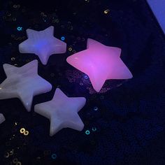 five star shaped candles sitting on top of a black table with blue and purple lights