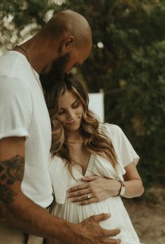 a man and woman standing next to each other holding their stomachs while looking at the camera