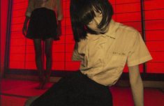 a woman sitting on the floor in front of two mannequins wearing short sleeves