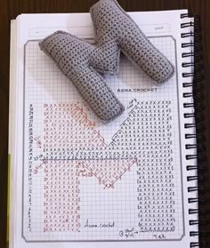 two pieces of fabric sitting on top of a notebook with cross stitching in it