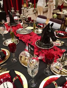 the table is set with red roses and black plates