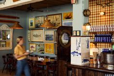 a man walking through a restaurant with lots of pictures on the wall