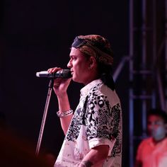 a woman standing on top of a stage holding a microphone in her hand and looking off to the side