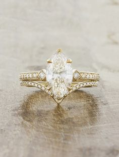 a pear shaped diamond engagement ring set on top of a wooden table