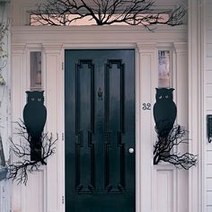 a black front door on a white house with two large vases in the window