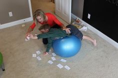 two people on the floor playing with some sort of ball and game pieces in front of them