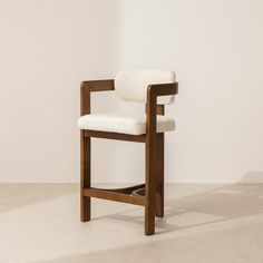 a wooden chair with a white upholstered seat and back rests against a wall