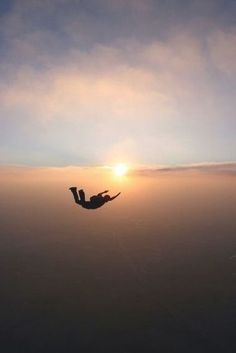 a person is flying in the air at sunset or sunrise with their feet off the ground