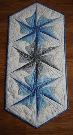 a blue and white quilted star on top of a wooden table