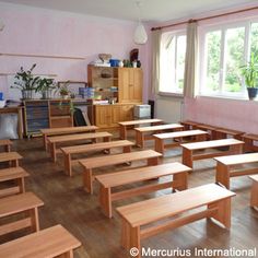 an empty classroom with wooden desks and benches