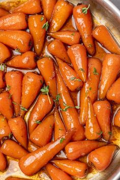 carrots are being cooked in a pan with brown liquid and parsley on top