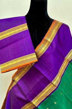 This stunning emerald green Kanjivaram silk saree is a handwoven masterpiece. The intricate gold zari buttas on the body add a touch of elegance, while the purple borders and grand pallu make for a striking contrast. Elevate your traditional wardrobe with this regal piece. Approximate Length 6.5 mtrs (inclusive of blouse length) Approximate Height - 48 - 52" Approximate weight - 1.6 lbs Saree comes with fall, picot and tassels done when applicable. Blouse piece is cut. Kindly Note : The colors you see on your device may vary due to the color reproduction, brightness and resolution of individual devices. If you'd like more clarity before your purchase, please contact our support team. Green Tussar Silk Saree With Border, Green Silk Traditional Wear With Border, Festive Green Saree With Border, Green Saree With Border In Traditional Drape, Ceremonial Green Tussar Silk Dupatta, Ceremonial Green Paithani Silk Saree, Green Silk Saree With Border, Traditional Purple Saree With Border, Green Bollywood Traditional Wear With Border