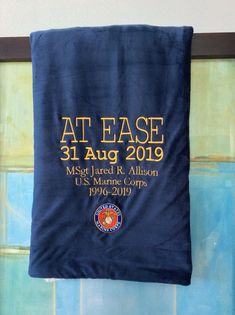 a blue towel hanging from the side of a wall with an at ease sign on it