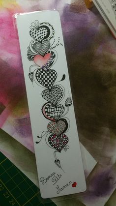 a bookmark with hearts on it sitting on top of a piece of paper next to scissors