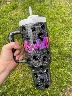 someone is holding up a black and pink tumbler with the word rachel on it