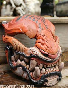 an orange and black dragon mask sitting on top of a wooden table