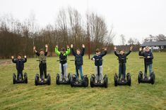 a group of children standing on segways with their hands in the air