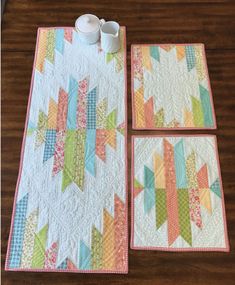 two quilted placemats with cups on them