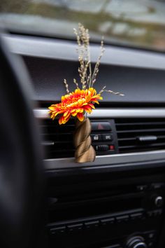 a car dashboard with an orange flower in the center and some brown stems sticking out of it