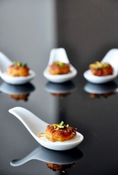 small appetizers are placed on spoons in the middle of a black table