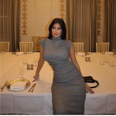 a woman standing next to a table with silverware on it