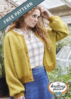 a woman wearing a yellow cardigan sweater and blue jeans standing in front of a greenhouse