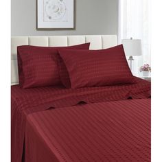 a bed with red sheets and pillows in a room