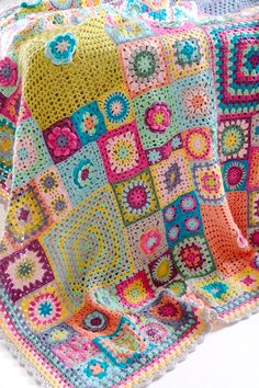 a colorful crocheted blanket is displayed on a white surface