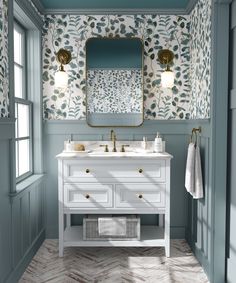 a bathroom with green cabinets and floral wallpaper on the walls, along with a gold framed mirror