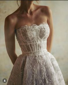 a woman wearing a white dress with silver sequins on the bust and shoulders