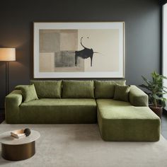 a living room with a large green couch and coffee table in front of a painting on the wall