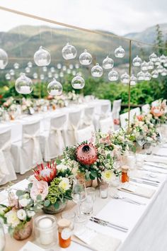 the tables are set up with flowers and bubbles hanging from the ceiling over them for an outdoor wedding reception