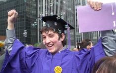 a young man wearing a purple graduation gown and holding his fist up in the air