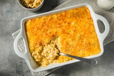 a casserole dish filled with macaroni and cheese next to a cup of milk