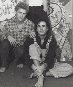 two men and a woman posing in front of graffiti