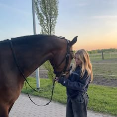 a woman standing next to a brown horse