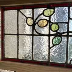 an old stained glass window with leaves and flowers on the bottom half, in a house