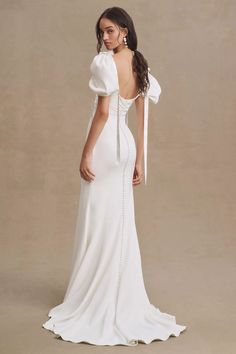 a woman in a white wedding dress is standing with her back to the camera