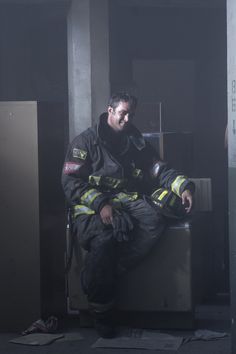 a fireman sitting on top of a metal box in the middle of a room