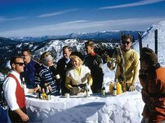 a group of people standing on top of a snow covered slope next to each other